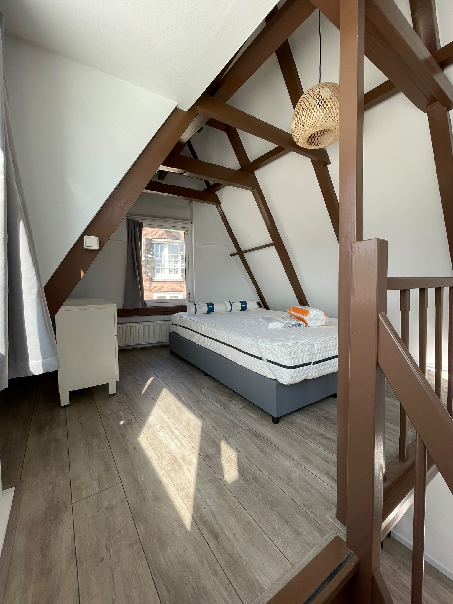 Slaapkamer onder het dak met houten spanten